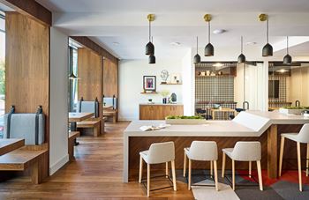 A large kitchen with white counter tops and chairs and a dining table